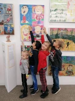 Kinder zeigen auf ihr Kunstwerk in einer Ausstellung